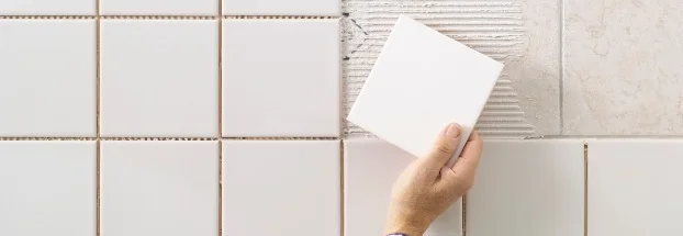 Hand befestigt Fliese an Wand